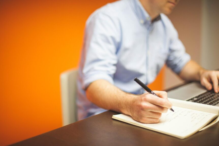 Man at a laptop with a notepad - ghostwriter